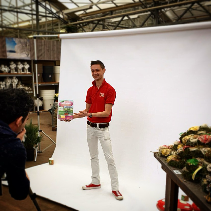 Ingmar Smit bei einem Fotoshooting im Gartencenter, im roten Poloshirt mit einem Produkt in den Händen.